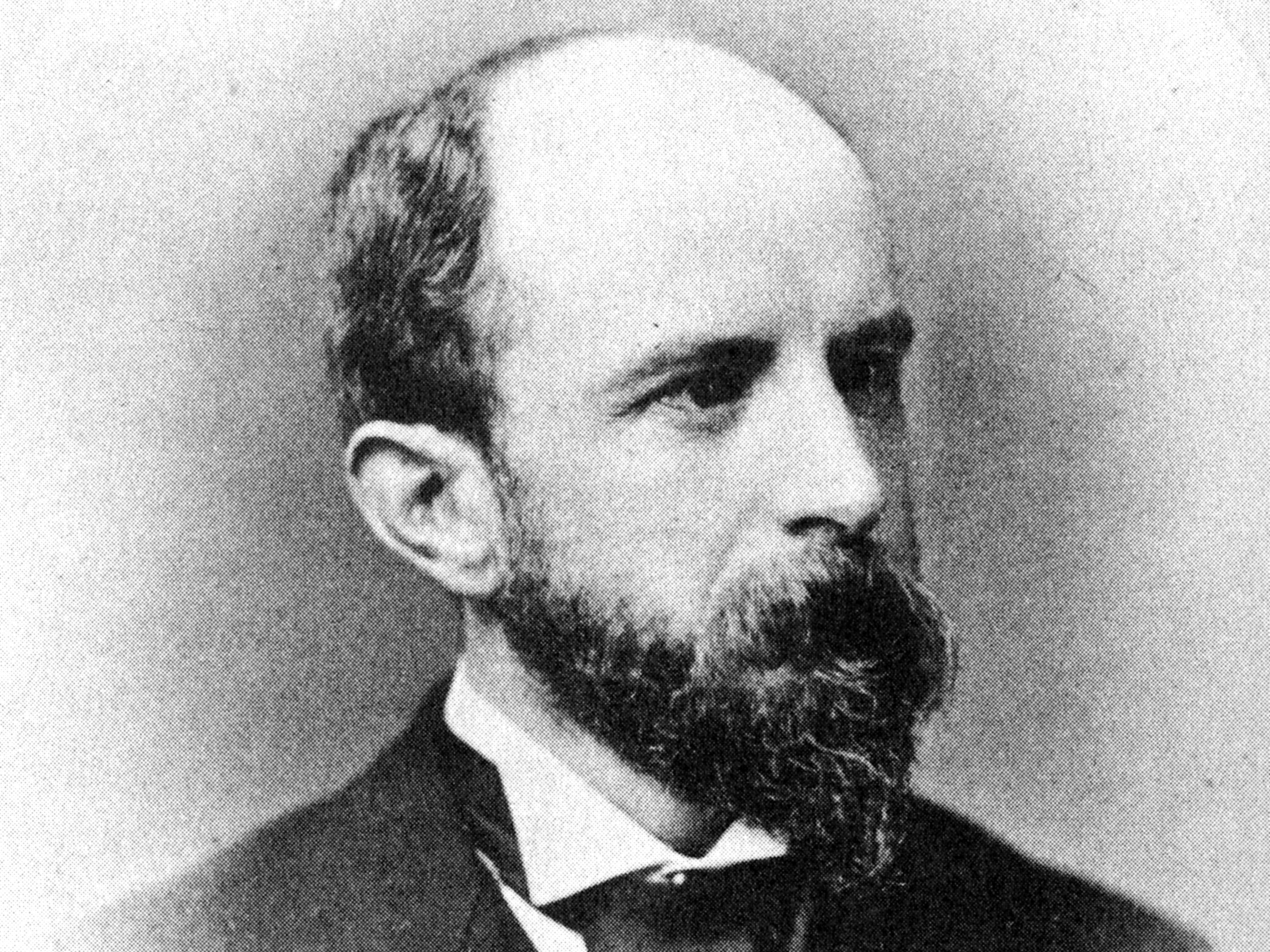 Ein Schwarz-Weiß-Porträt von Henry Brooks Adams, der Anzug und Krawatte trägt und nach links blickt.