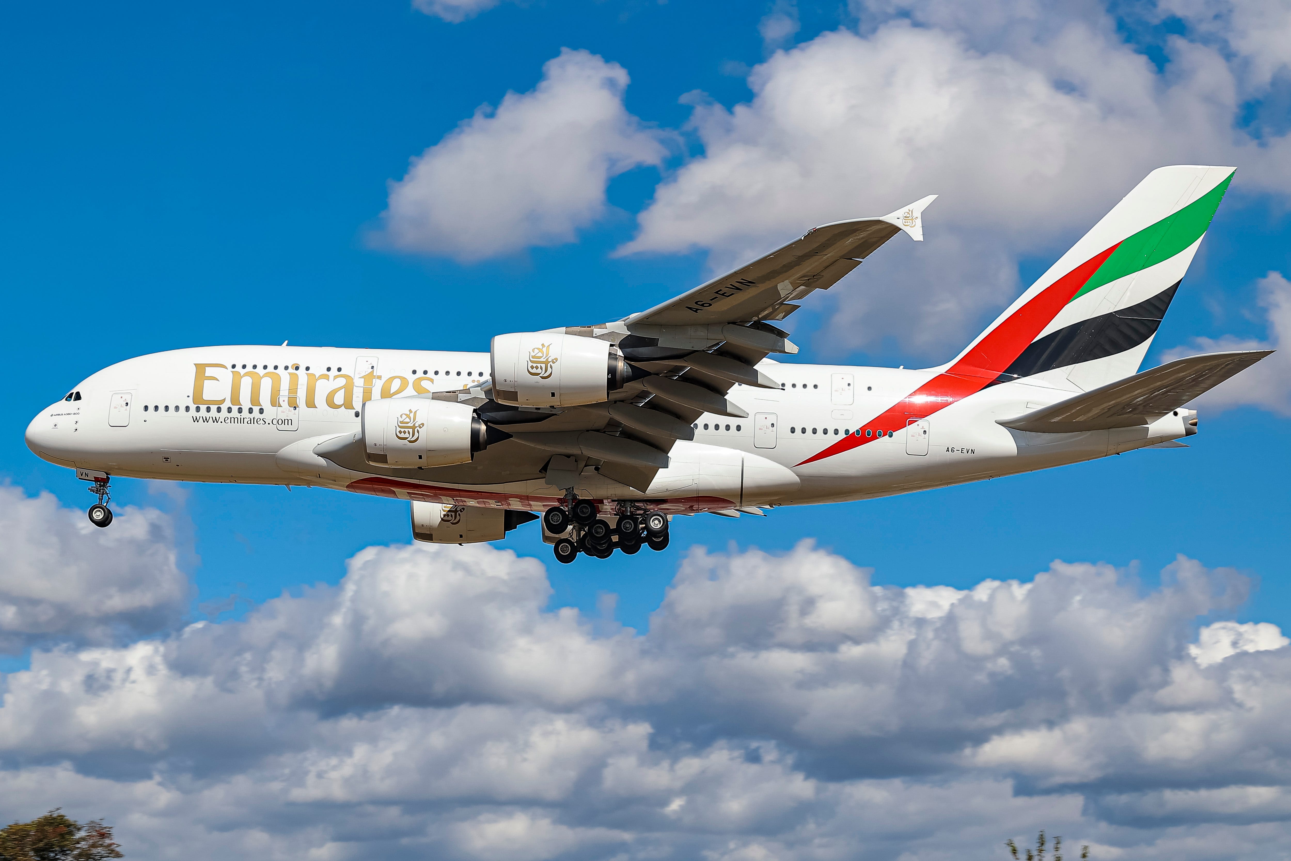 Emirates Airbus A380-Flugzeuge, wie sie an einem sonnigen Sommertag mit blauem Himmel und einigen Wolken im Endanflug zum Flughafen Heathrow fliegen,