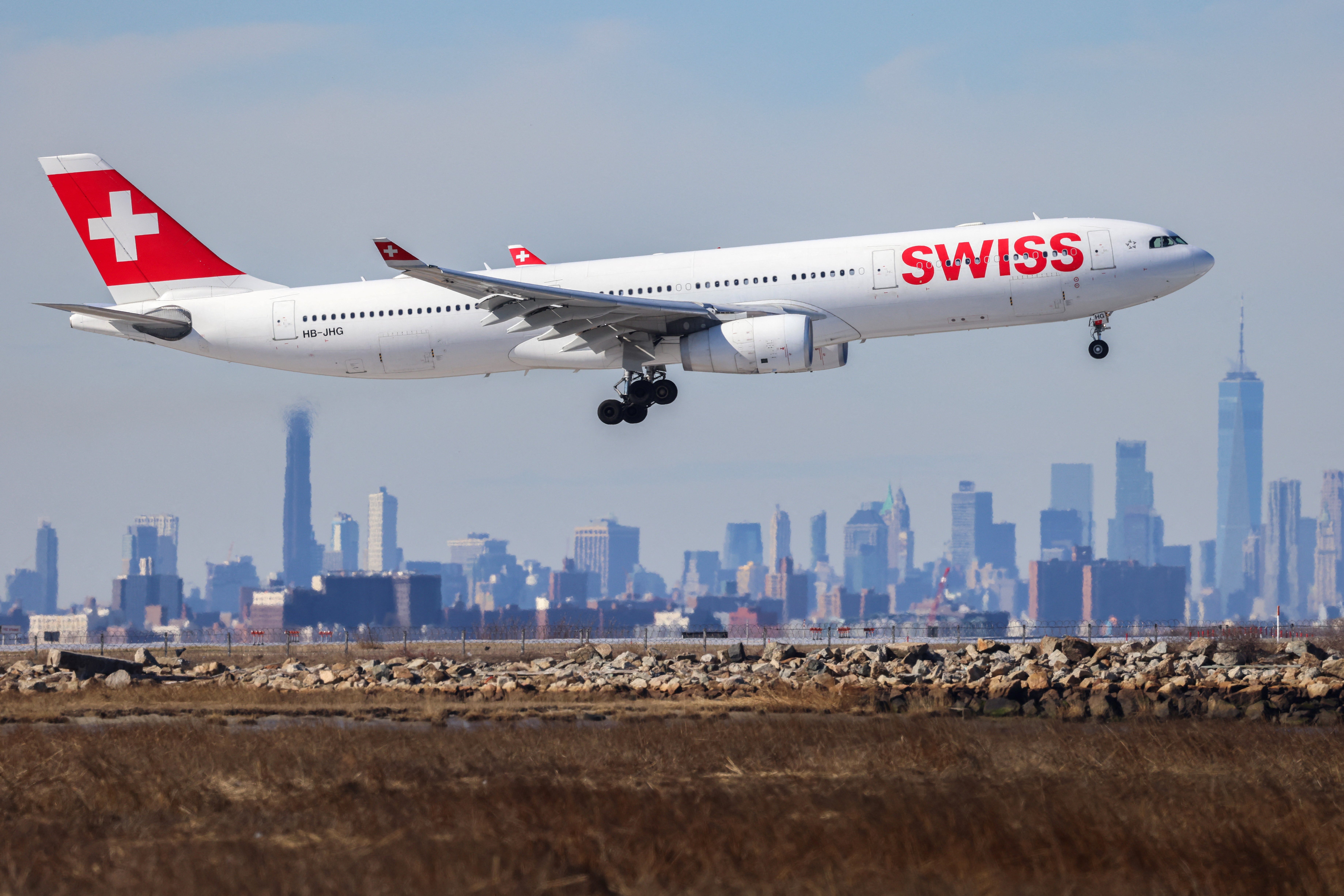 Ein Passagierflugzeug vom Typ Airbus A330 der Swiss Airlines landet am 7. Februar 2024 aus Zürich am JFK International Airport in New York, im Hintergrund zeichnet sich die Skyline von Manhattan ab.