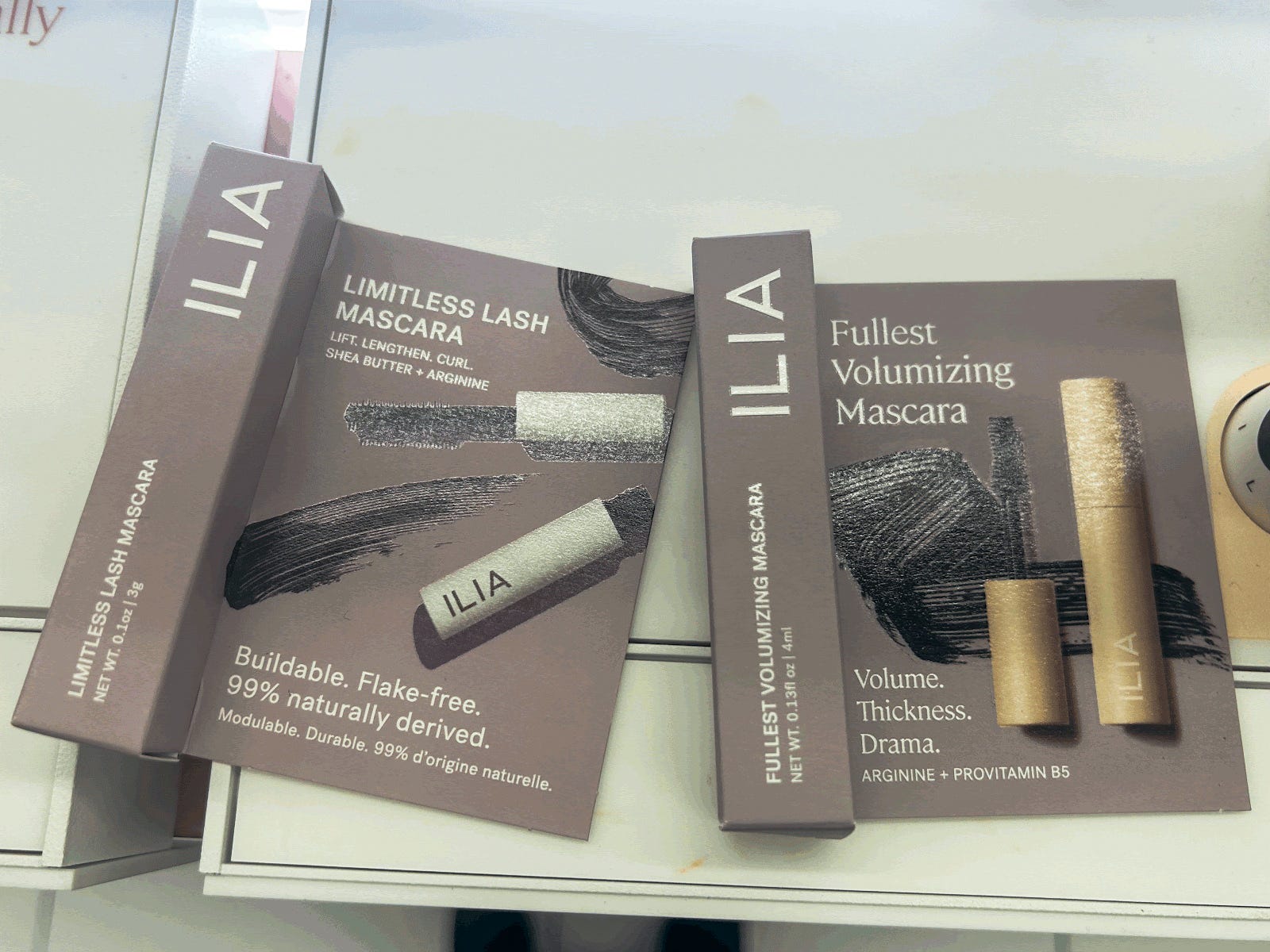 Zwei graue Kartonschachteln mit Ilia-Mascara.  Auf einer Packung steht „Limitless Lash Mascara“ und auf der anderen „Fullest Volumizing Mascara“.