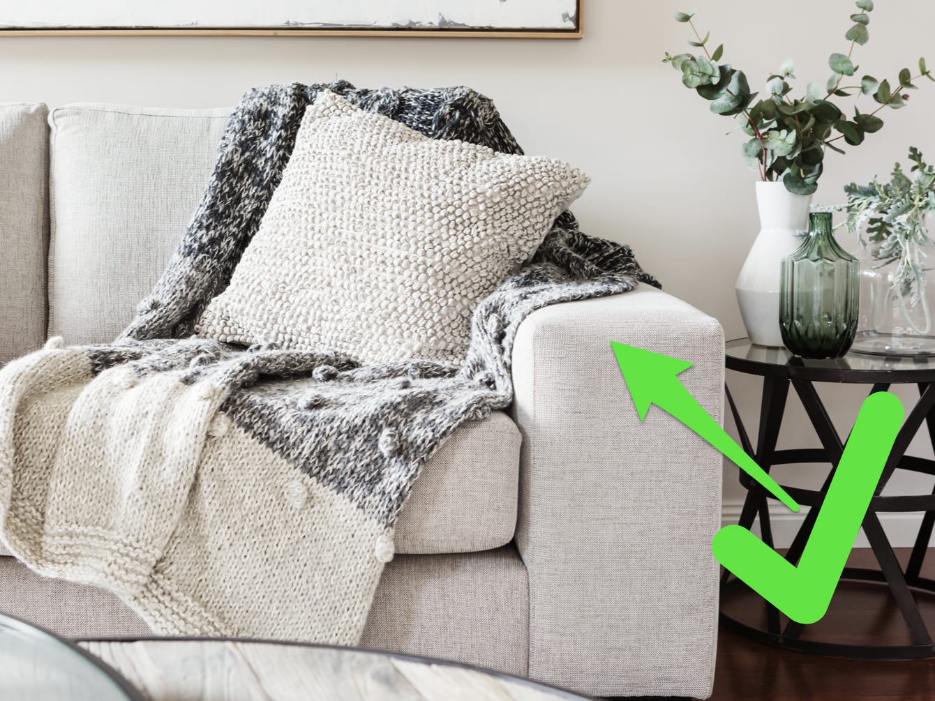 Wohnzimmer mit einer weißen Couch mit strapazierfähigem Stoff und einem grünen Pfeil und Häkchen, der auf die Couch zeigt