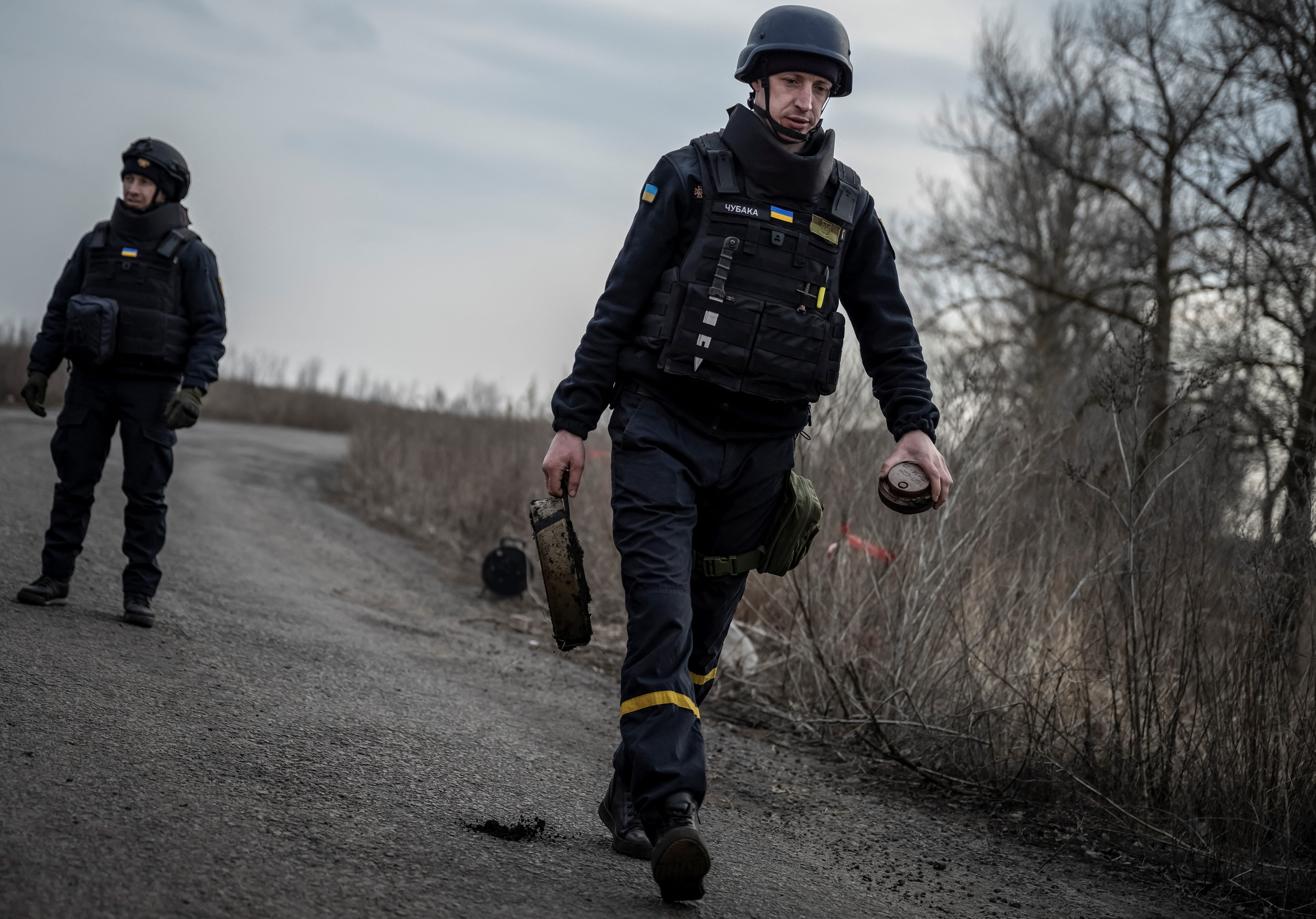 Ein Pionier des staatlichen Notdienstes trägt eine Panzerabwehrmine bei sich, während er ein Gebiet nach Minen und nicht explodierten Granaten inspiziert, während Russlands Angriff auf die Ukraine am 21. März 2023 in der Region Charkiw, Ukraine, andauert.