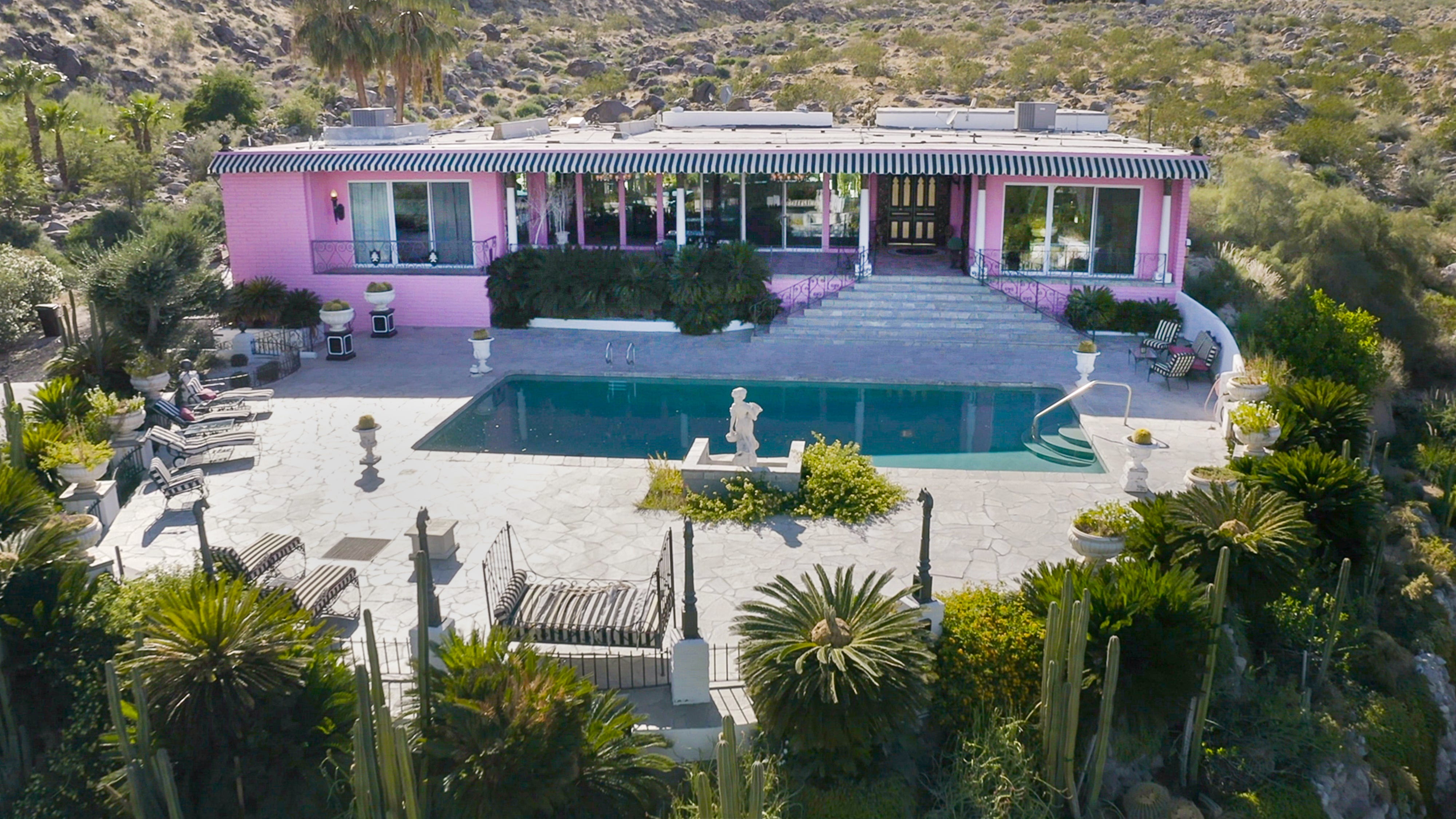 Der Palm Springs Pink Palace mit Marmorstatuen und einem Swimmingpool im Vorgarten