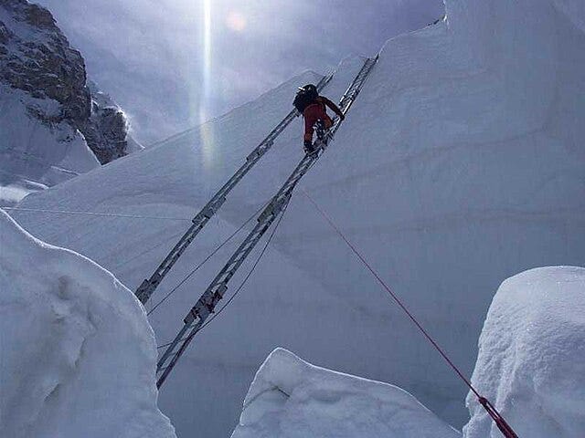 Ein Kletterer erklimmt eine Leiter im Khumbu-Eisbruch
