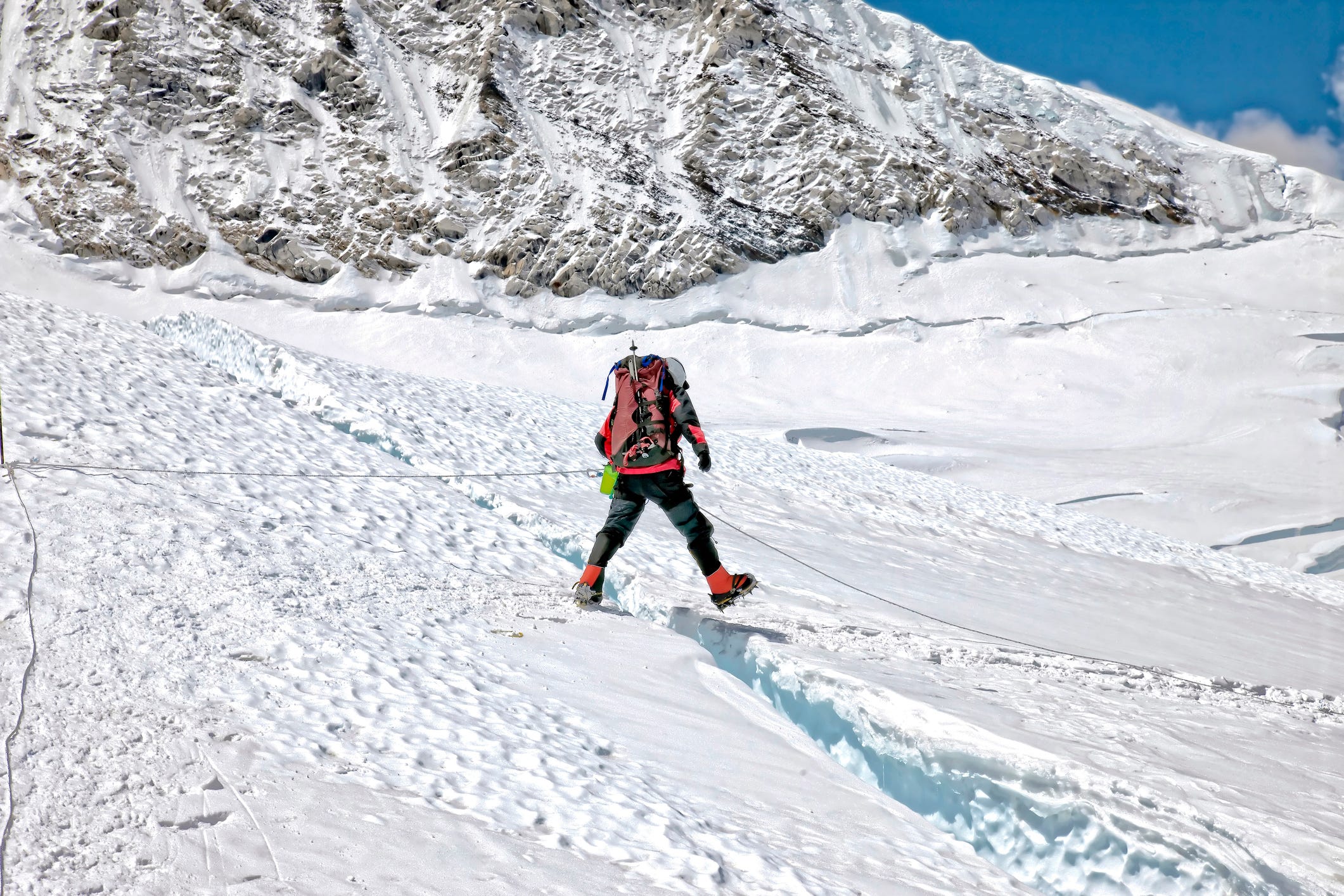 Bergsteiger steigt über eine kleine Gletscherspalte über den schneebedeckten Khumbu-Eisbruch am Mount Everest