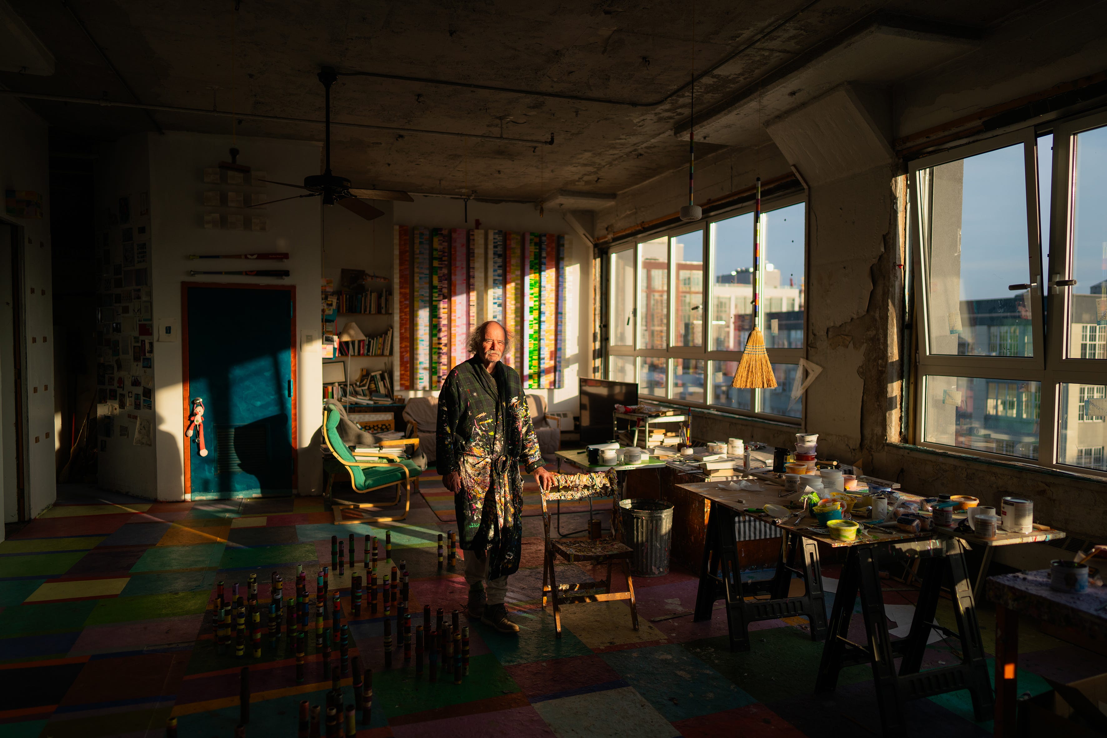 Steve Silver steht im Bademantel im Schatten, der durch sein farbenfrohes Studio in Williamsburg strömt.