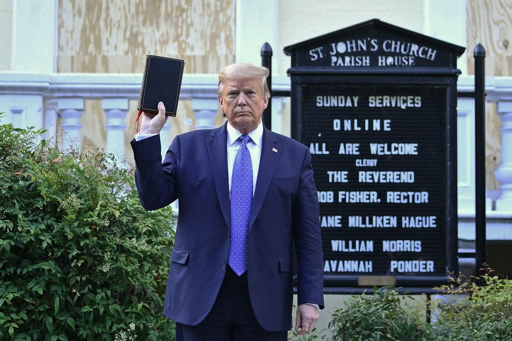 Donald Trump steht vor einer Kirche und hält eine Bibel in der Hand