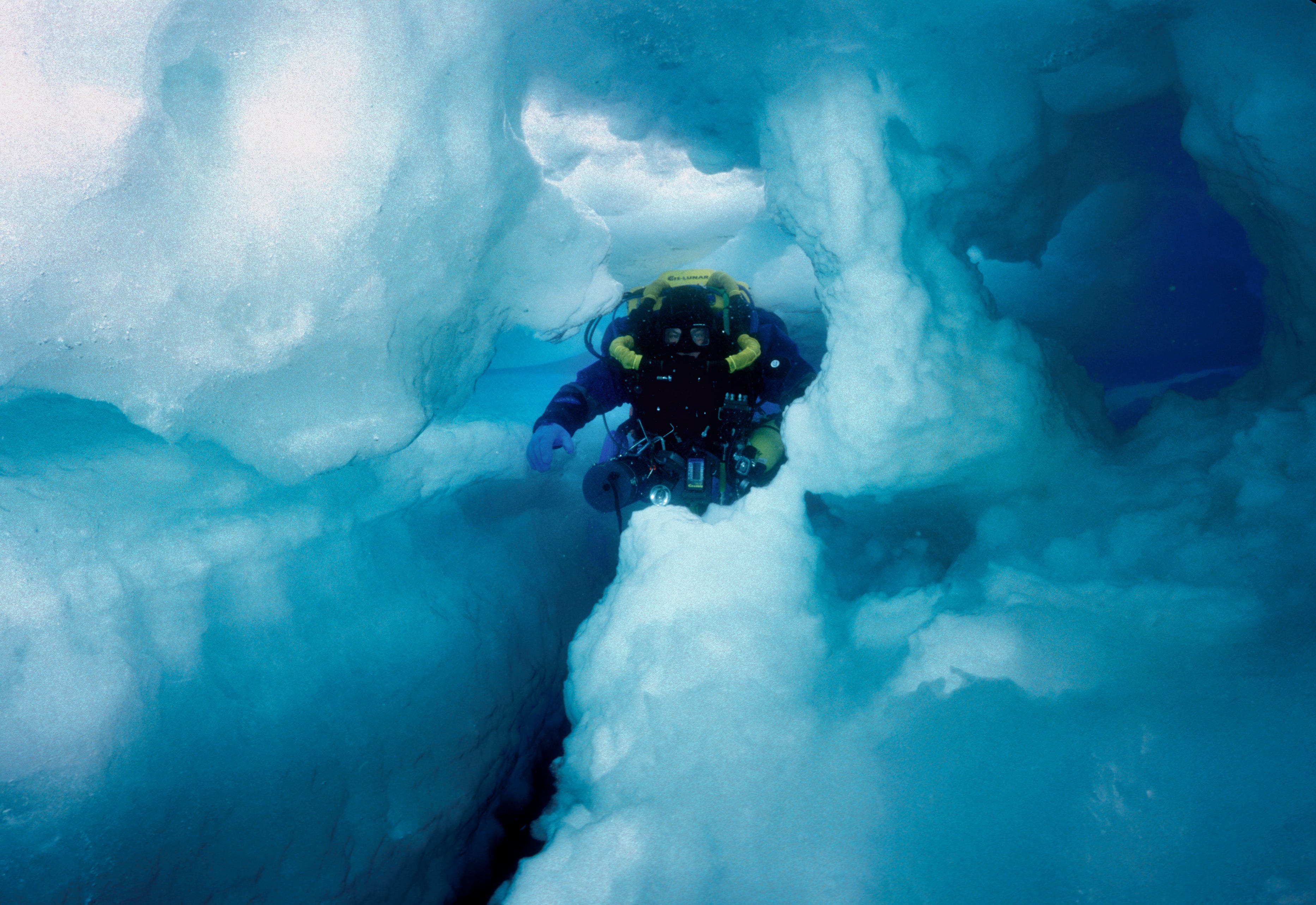 Ein Taucher schwimmt durch eine enge Spalte im Eisberg B15
