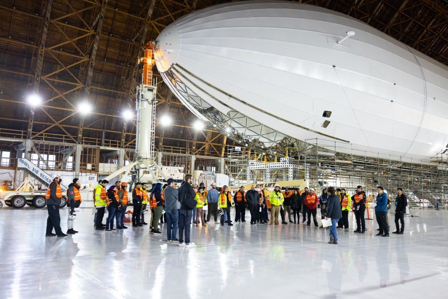 Eine Gruppe von Arbeitern in einem großen Lagerhaus steht vor dem von LTA Research entwickelten Luftschiff Pathfinder 1.
