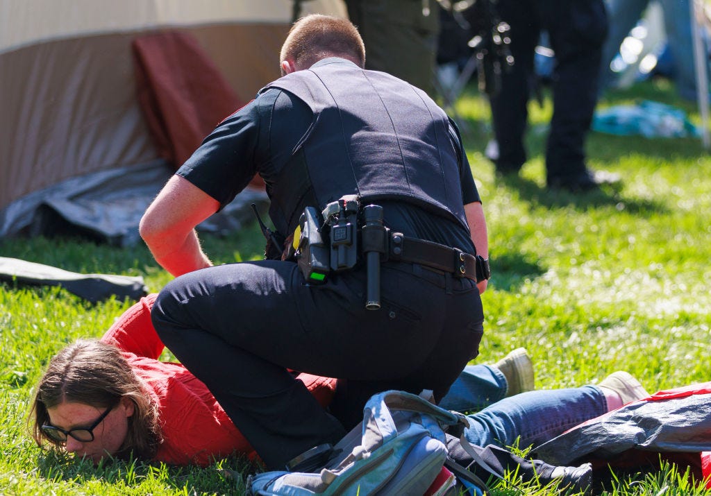 Eine Person wird von einem Polizisten am Boden festgehalten