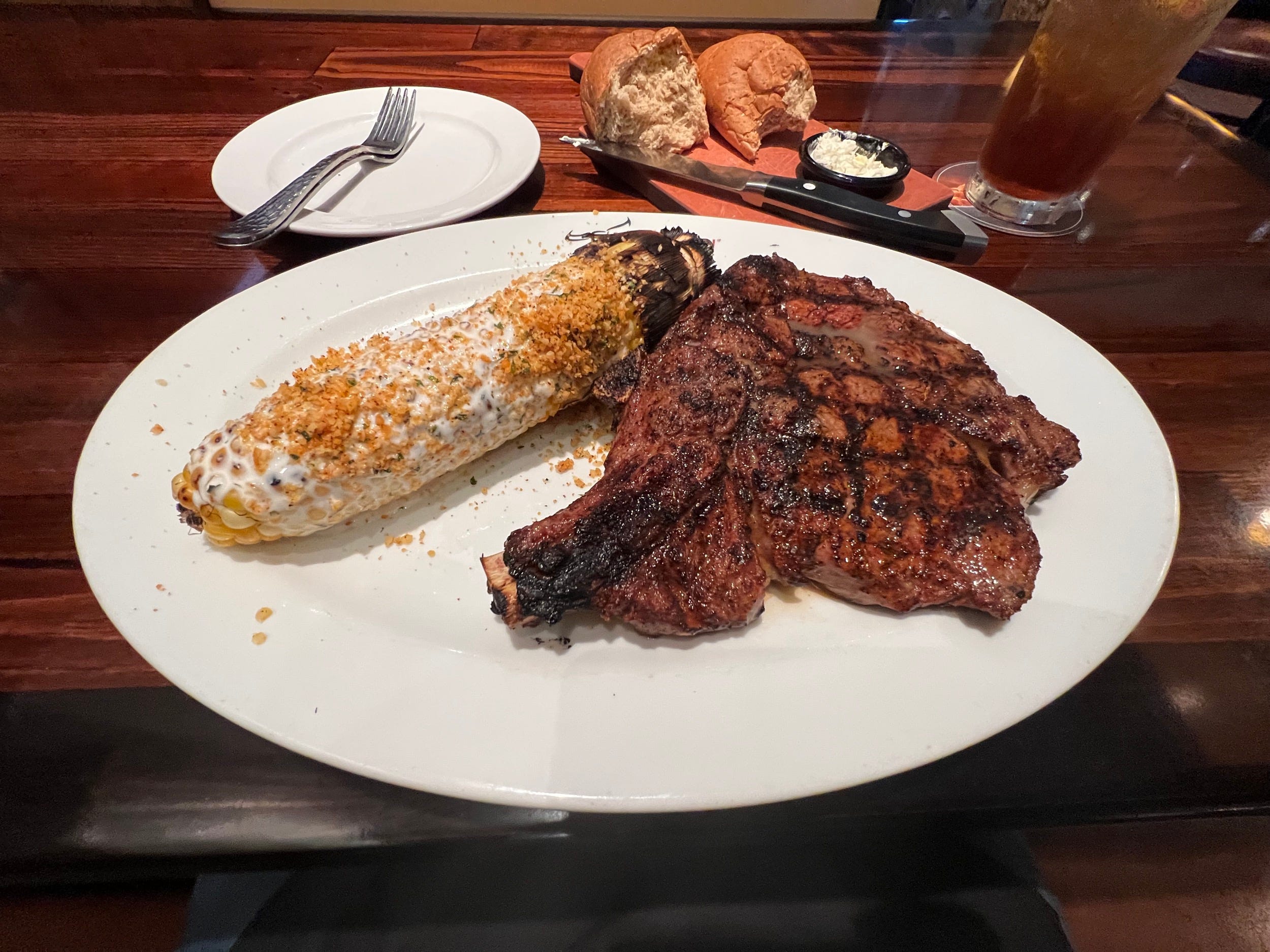 Ein Longhorn Steakhouse-Ribeye mit Knochen und einer Beilage Maiskolben