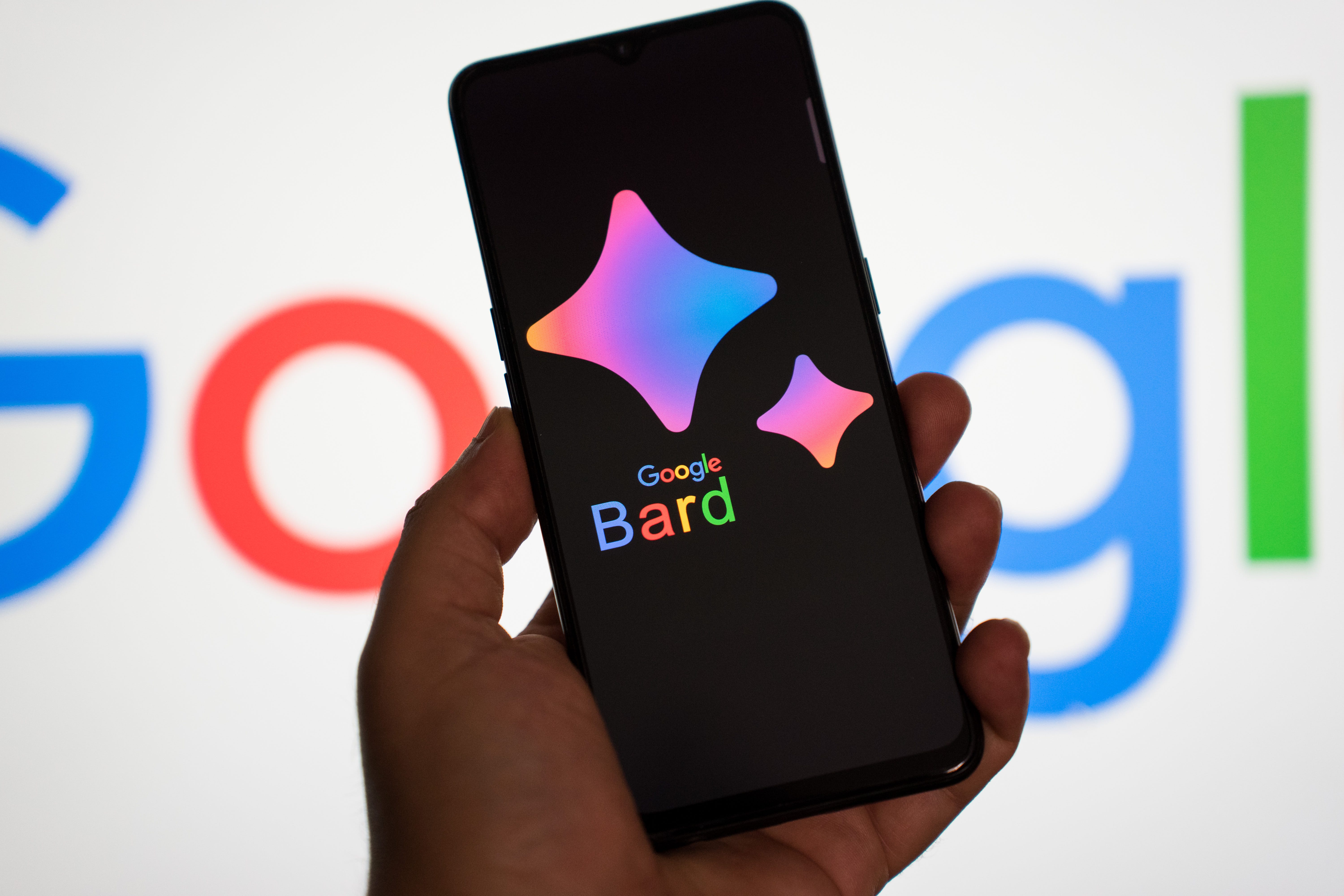 Auf einem Smartphone wird das Google Bard-Logo vor einem Hintergrund mit dem Google-Logo angezeigt.