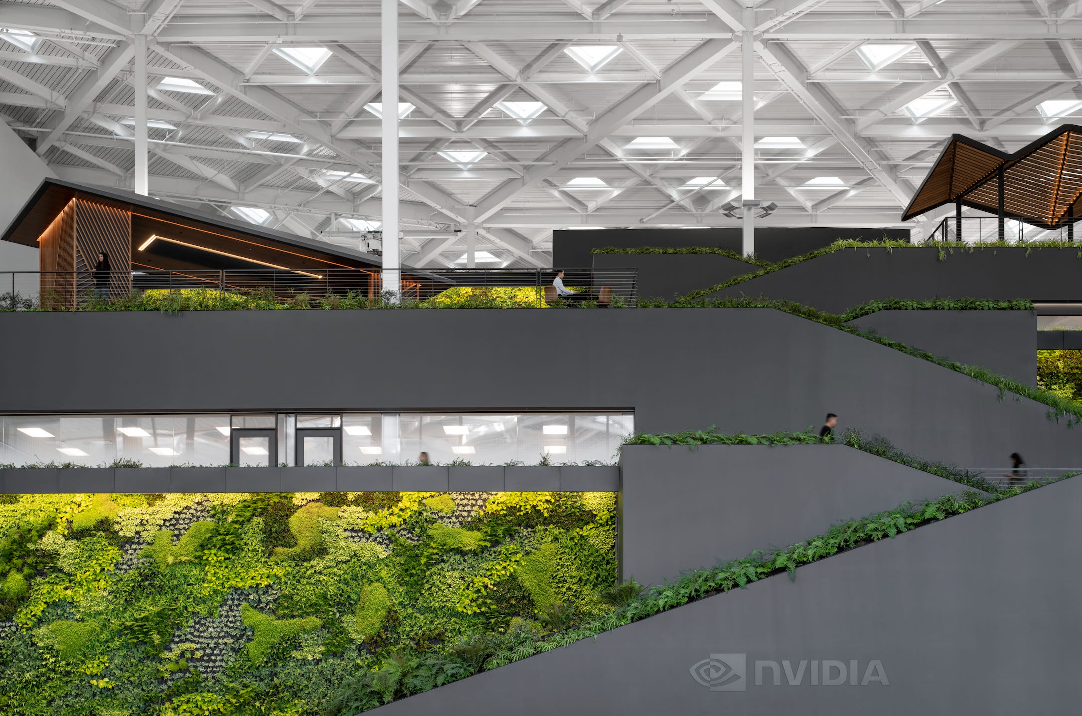 graue Gänge im Nvidia-Hauptquartier, die von viel Grün und dreieckigen Fenstern auf dem Dach umgeben sind