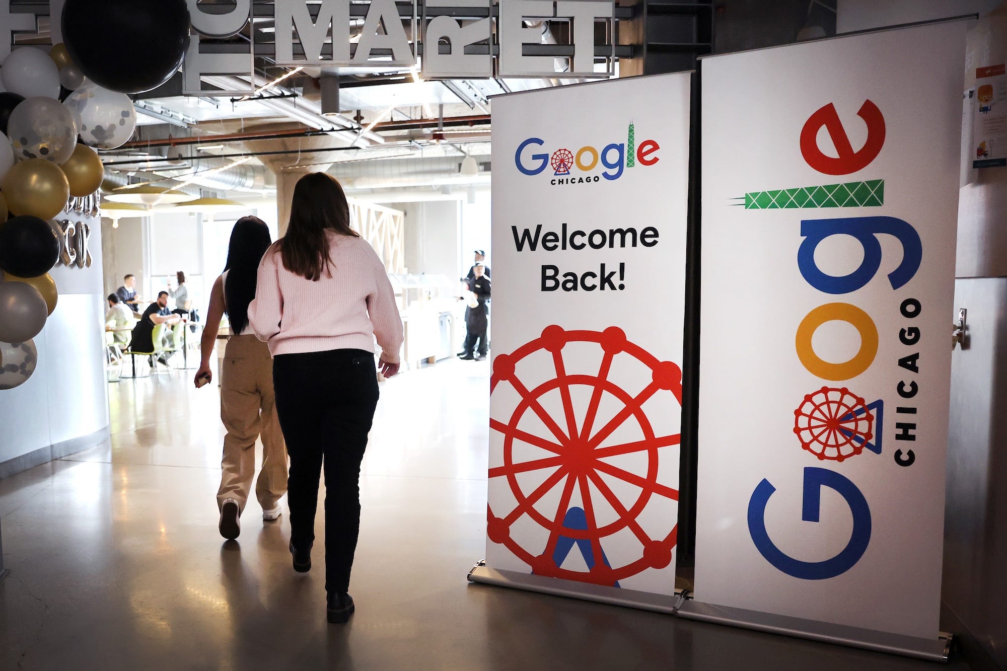 Google-Mitarbeiter betreten eine Cafeteria in der Google-Zentrale in Chicago, vorbei an einem Schild mit der Aufschrift „Willkommen zurück!“
