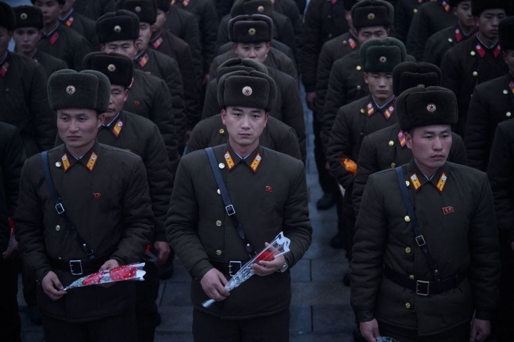 Soldaten der Koreanischen Volksarmee (KVA) halten Blumen hoch, während sie vor einer Statue des verstorbenen nordkoreanischen Führers Kim Jong Il ihre Aufwartung machen.