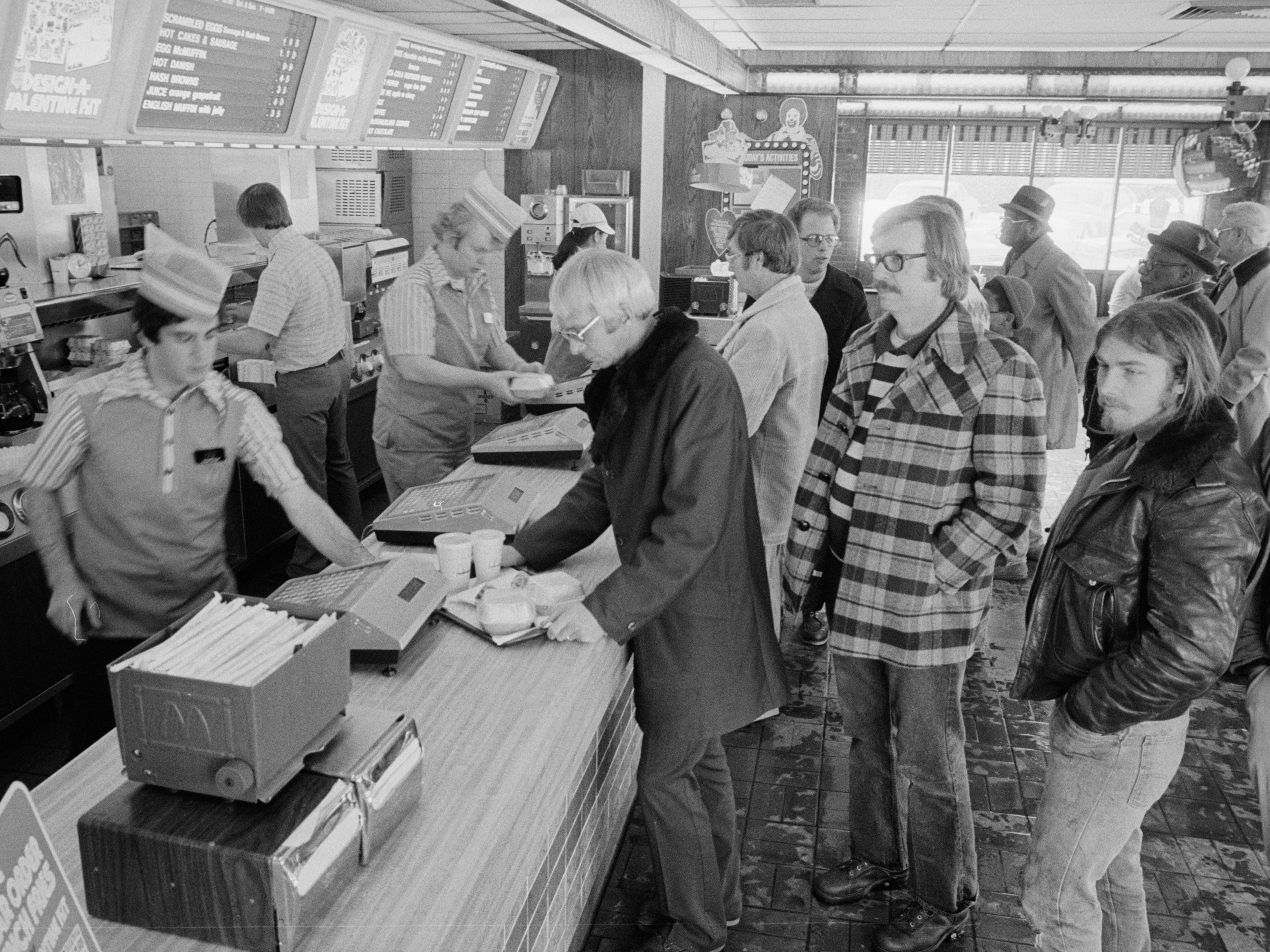 Blick entlang der Theke eines McDonald's-Schnellrestaurants, während Mitarbeiter 1979 eine Reihe von Kunden bedienen