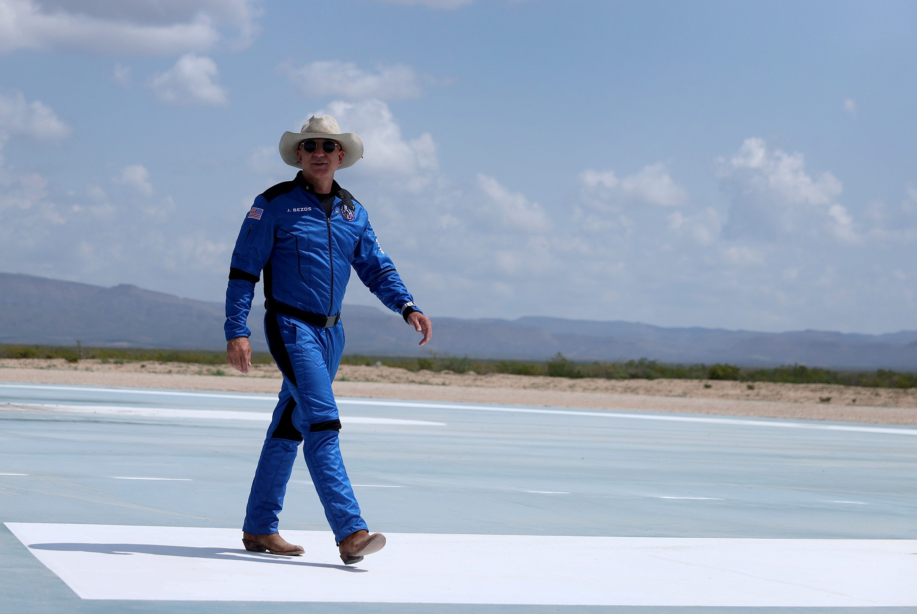 Jeff Bezos trägt einen Cowboyhut und einen blauen Overall von Blue Origin