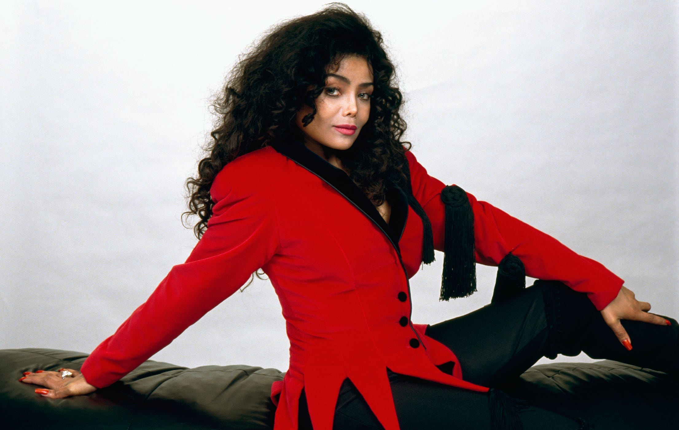 La Toyla Jackson auf einer Couch in einem roten Mantel