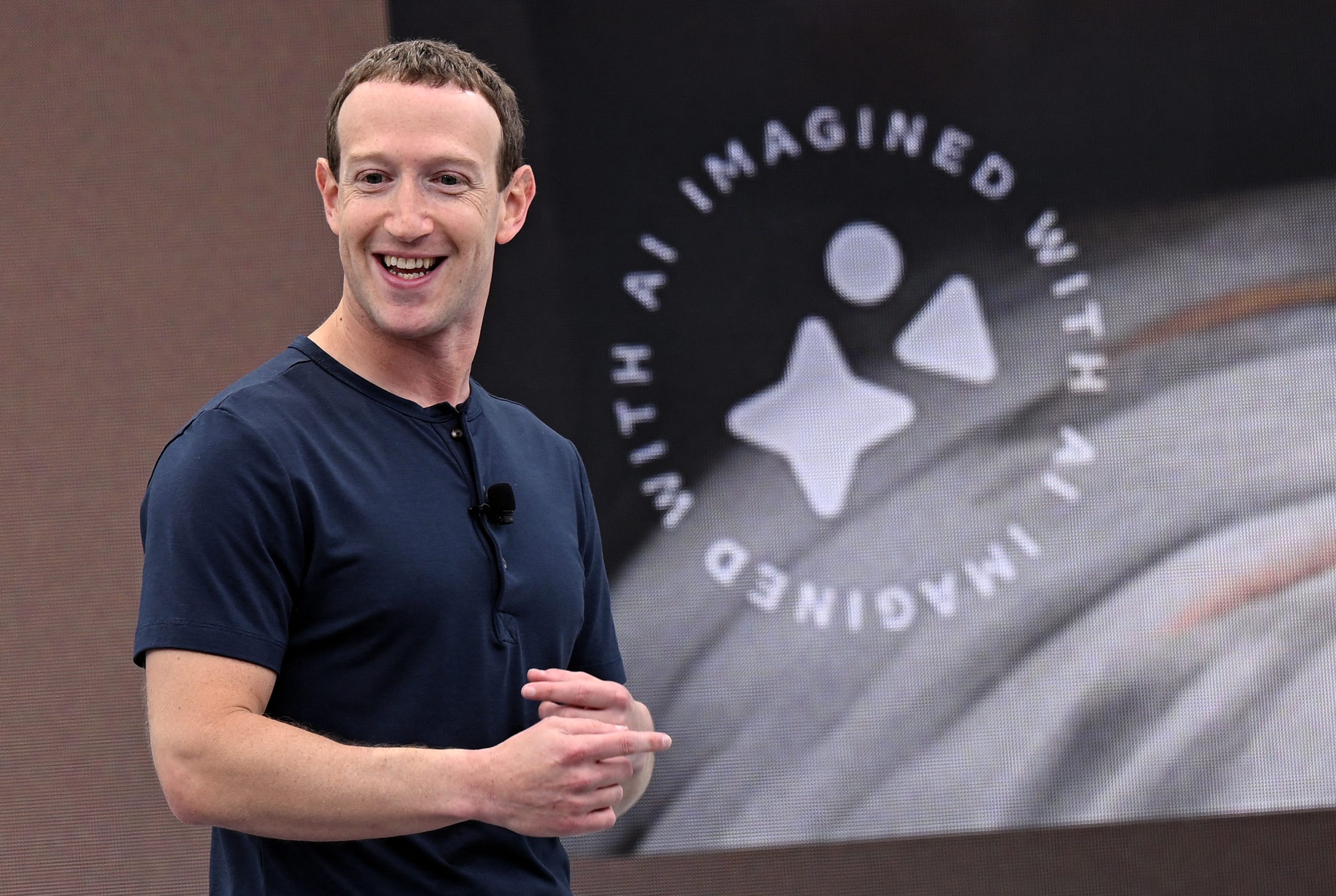 Mark Zuckerberg steht vor einer Grafik mit der Aufschrift „KI, vorgestellt mit KI“.