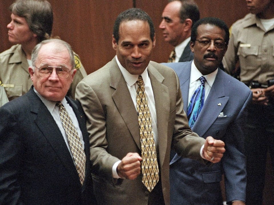 OJ Simpson cheers in a courtroom. 