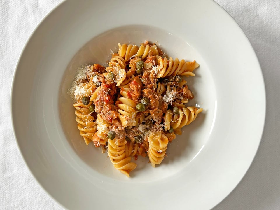 Plate with fusilli pasta, tomato sauce and grated cheese.