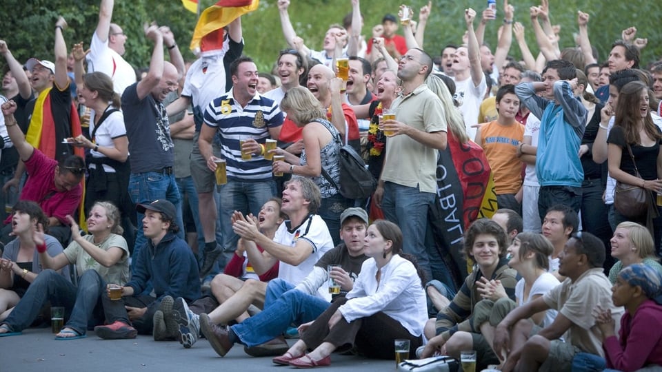 Football fans in a public square cheer and drink beer.