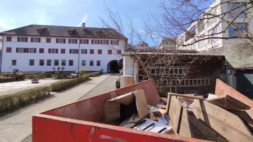 Renovation work with containers and building materials in front of a historic building.