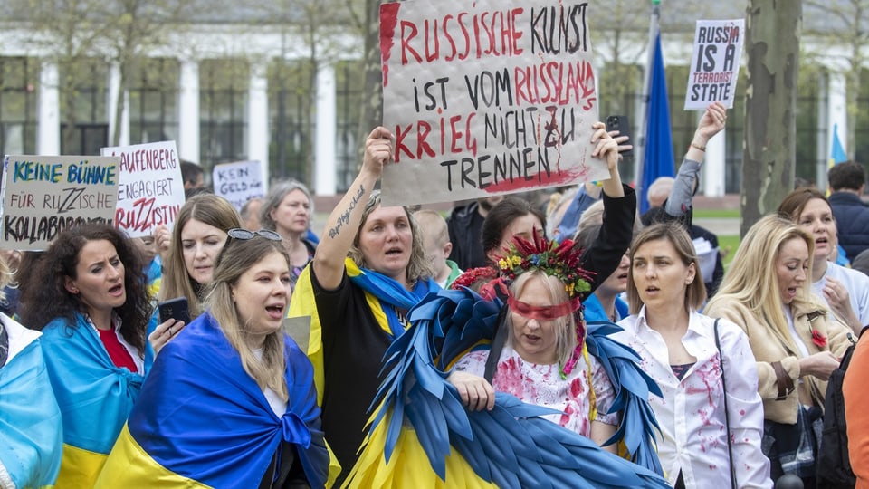 Women hold cardboard signs.  It says: “Russian art cannot be separated from the Russian War.”