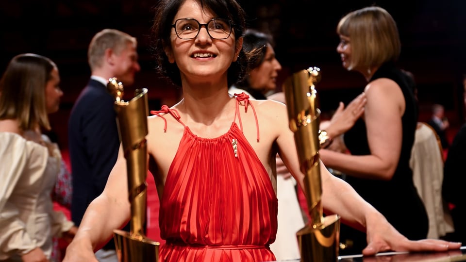 Director Ayse Polat and two awards standing in front of her.