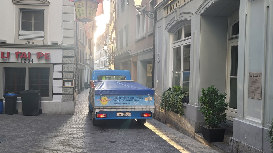 A delivery truck drives through a narrow alley.