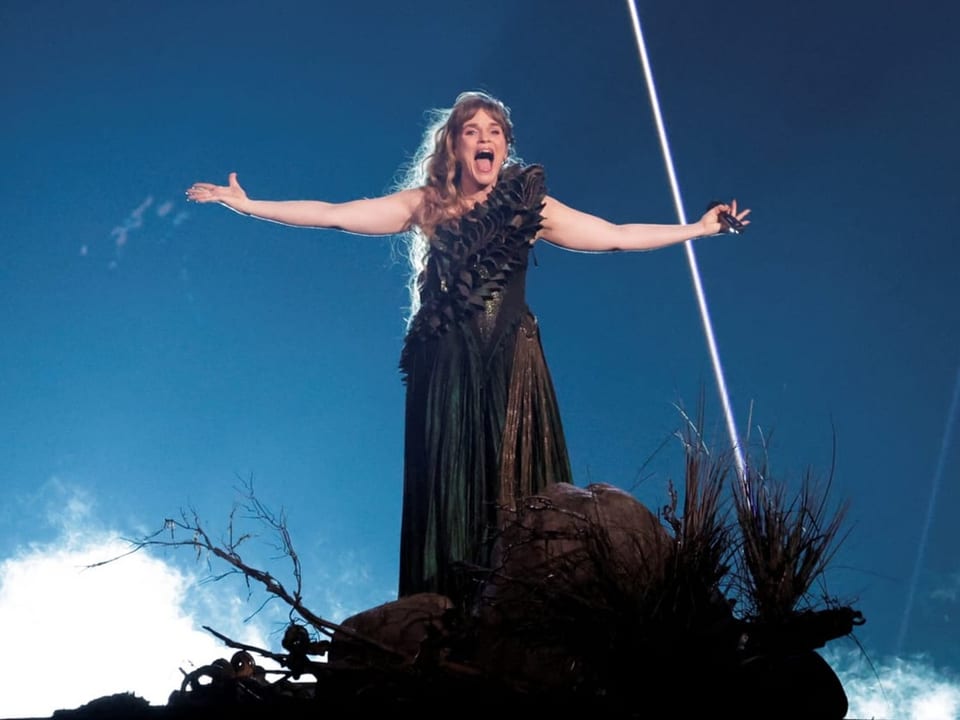 Sängerin in historischem Kostüm singt leidenschaftlich auf einer Bühne mit dramatischer Beleuchtung