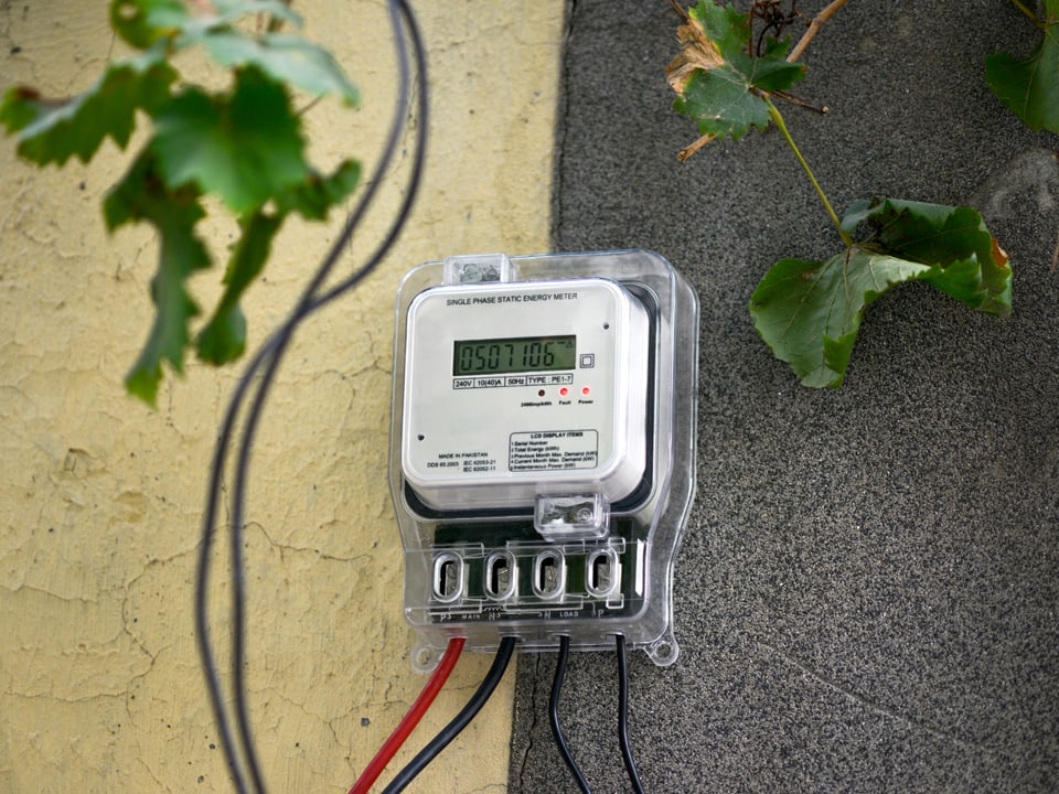 A smart meter hangs on a house wall