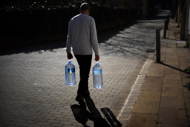 A man carries two cans filled with water to a natural spring in Gualba, in the Barcelona region, (Spain), January 31, 2024. 