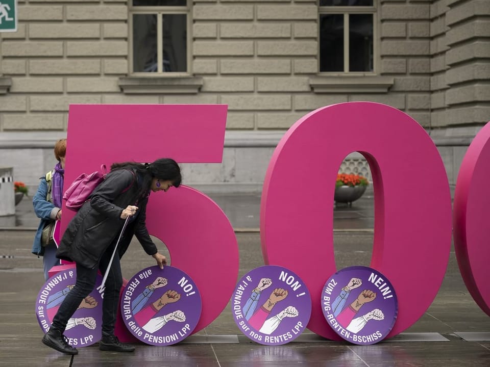 Person protesting in front of a large pink 500 sign.