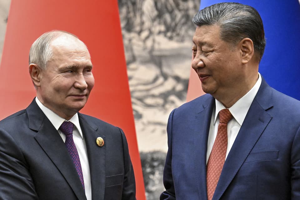 Putin on the left, smiling, Xi Jinping on the right, smiling, looking at each other.