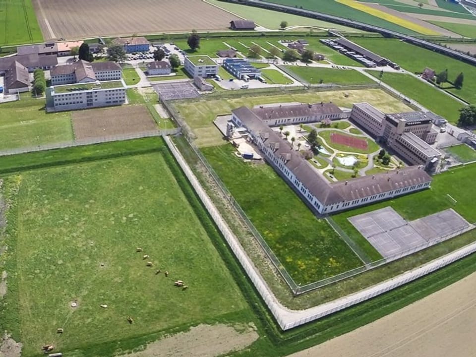 Bird's eye view of prison complex, surrounded by green meadows and agricultural land